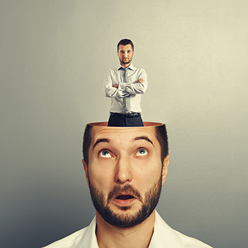 surprised young man looking up at serious small man in his head over grey background
