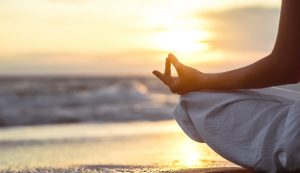 Person meditating on the shore.